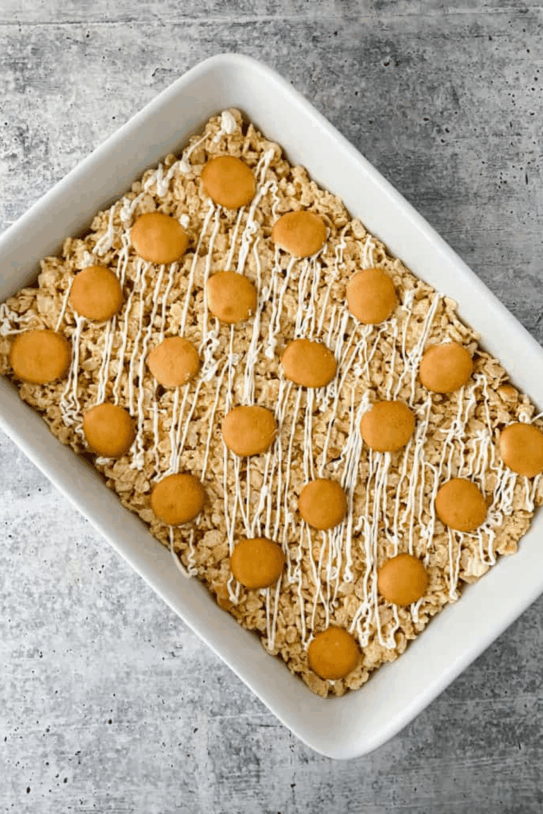 Tray of Instant Pot Banana Pudding Rice Krispie Treats, drizzled with white chocolate and topped with crushed vanilla wafers, ready to serve.