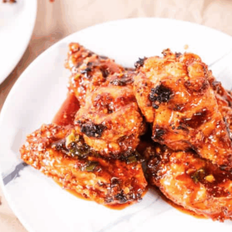 Air Fryer Korean Chicken Wings coated in spicy glaze and garnished with sesame seeds and green onions