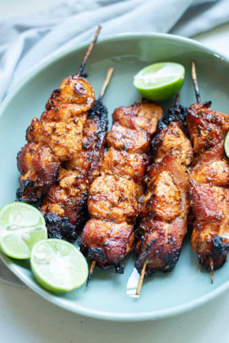Air fryer bacon wrapped chicken tenders on a white plate with dipping sauce