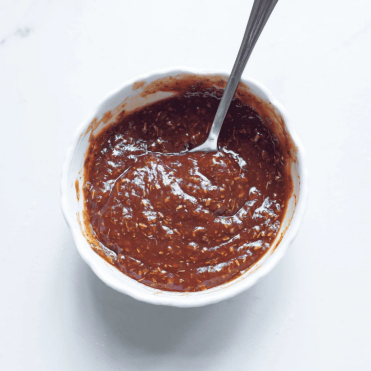 BBQ sauce in a small white bowl with a spoon for air fryer bacon wrapped chicken tenders