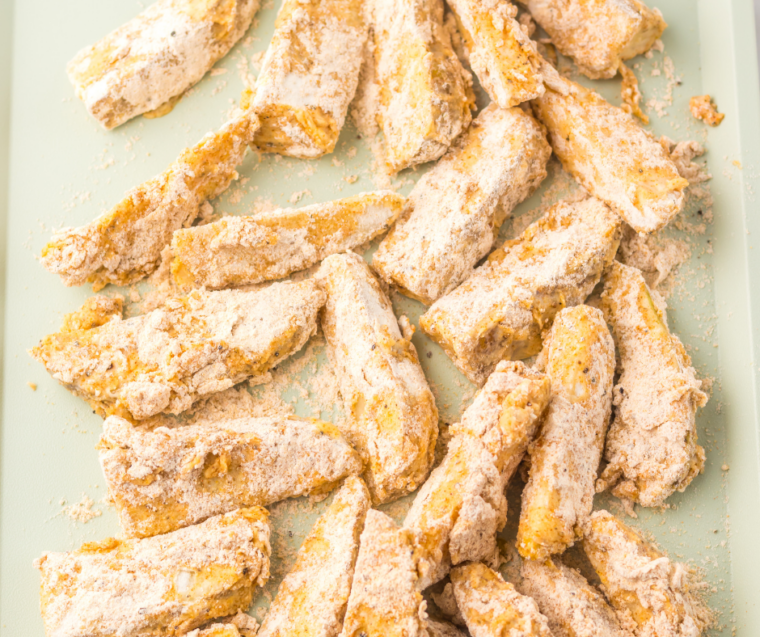 Coated potato wedges arranged in a single layer in an air fryer basket before cooking