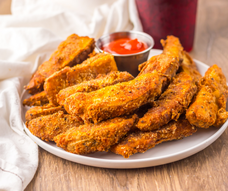 Hot potato wedges tossed with buffalo wing sauce in a large bowl