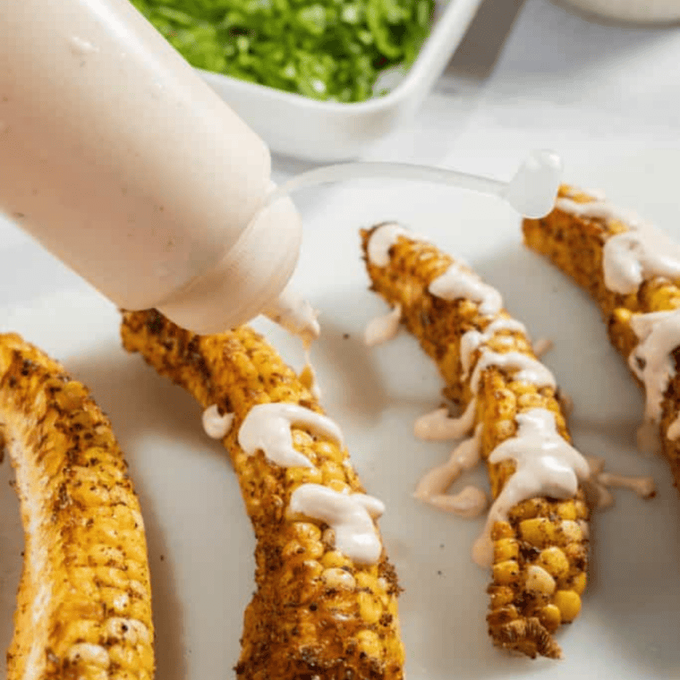 Corn ribs drizzled with chipotle mayo and topped with crumbled cotija and chopped cilantro