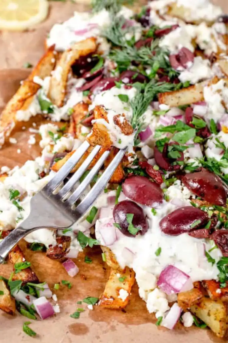 Overhead view of air fryer Greek fries on a serving platter with a side of creamy tzatziki for dipping