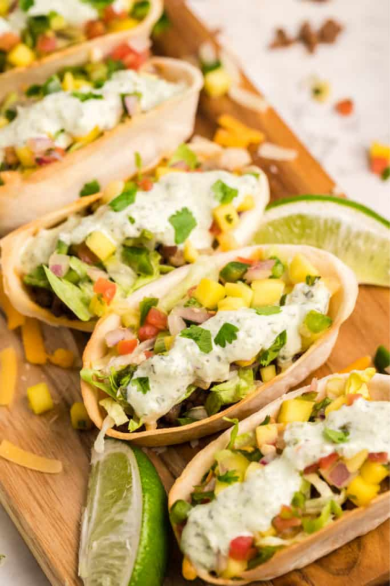 Air fryer ground beef taco bowls topped with lettuce, cheese, and pico de gallo