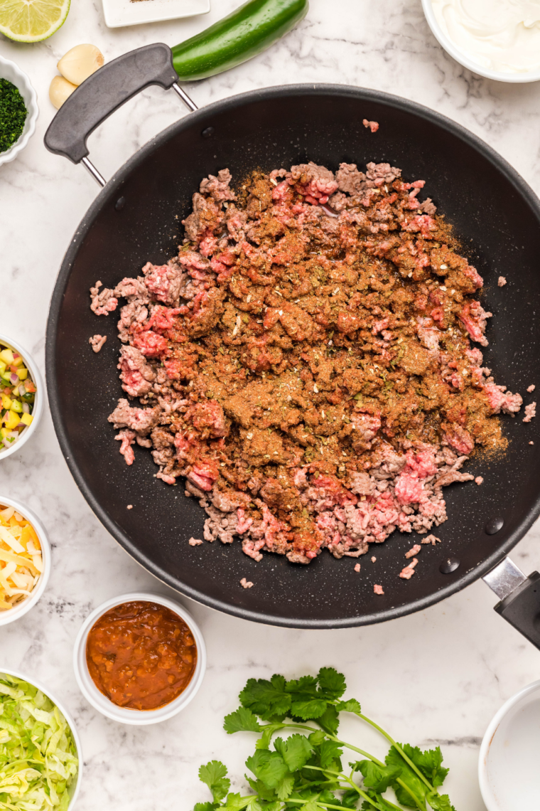 Brown the beef: Seasoned ground beef browning and crumbled in a skillet for taco bowls