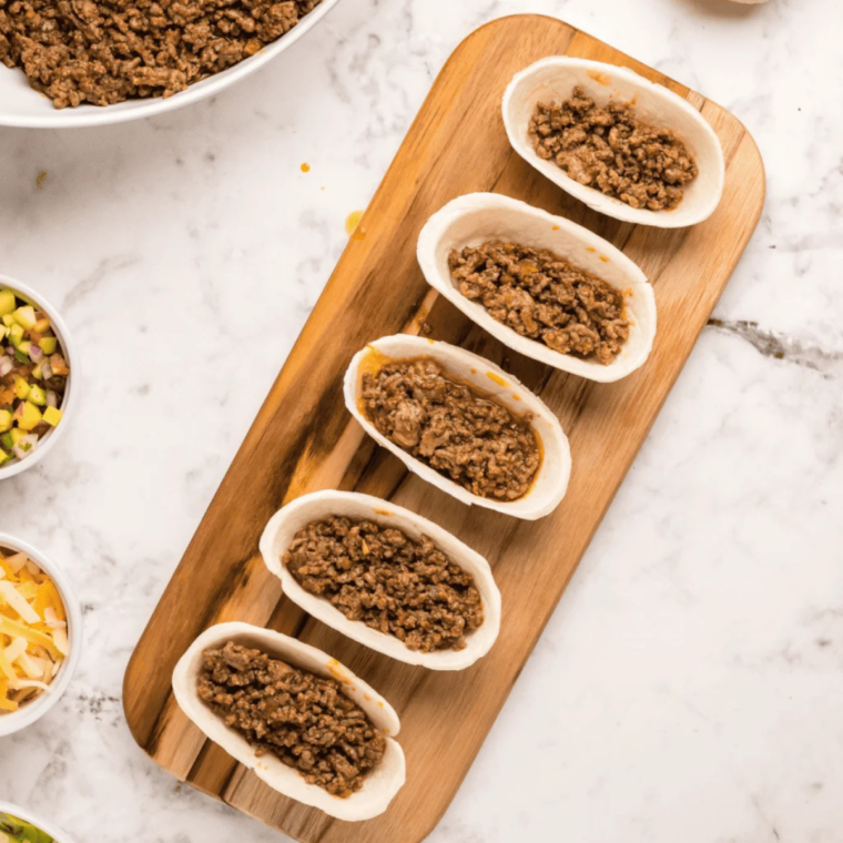 Fill and air fry: Mini taco bowls filled with seasoned beef and shredded cheese in an air fryer basket