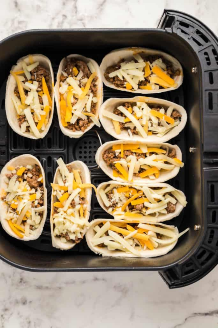 Add toppings and serve: Air fryer ground beef taco bowls topped with lettuce, pico de gallo, and cilantro-lime sour cream