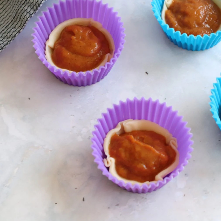 Spooning pumpkin filling into mini tart crusts