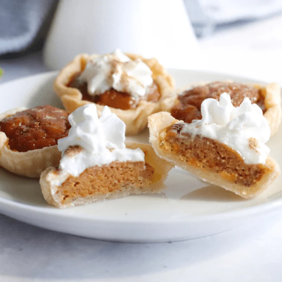 Air fryer pumpkin tarts topped with whipped cream on a white plate