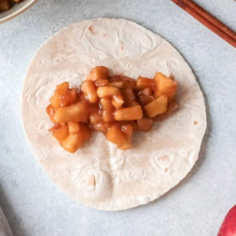 Apple filling spooned in a line down the center of a flour tortilla