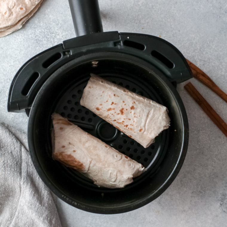 Rolled apple flautas arranged seam side down in an air fryer basket