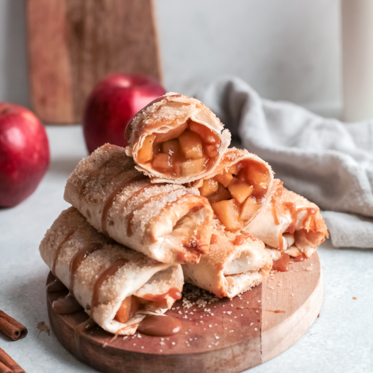 Crispy apple flautas on a white plate drizzled with salted caramel sauce