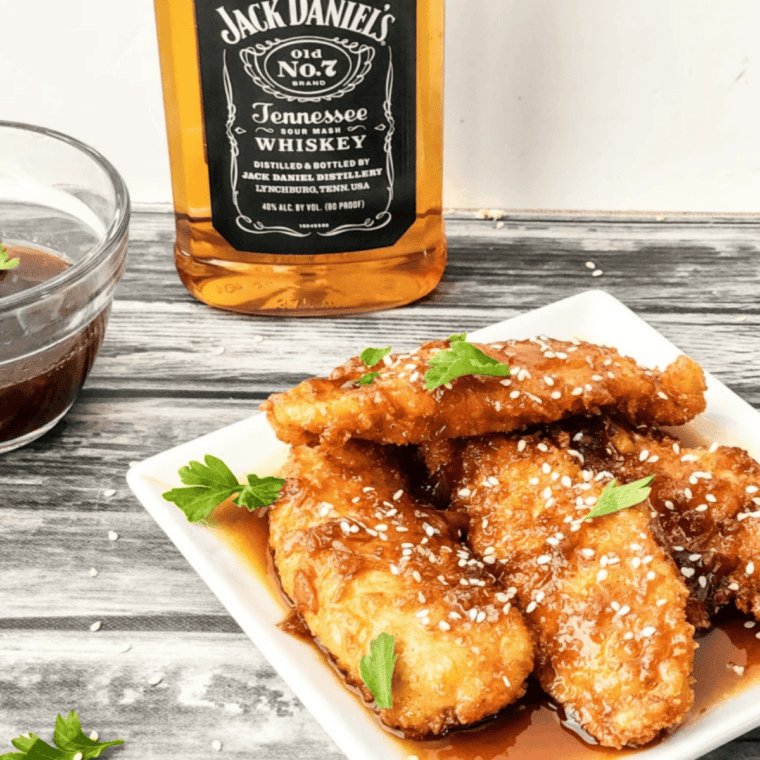 Copycat Jack Daniel's chicken strips glazed with sticky whiskey sauce and sprinkled with sesame seeds.
