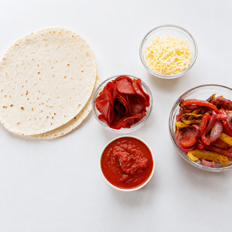 Ingredients for air fryer turkey wraps: flour tortillas, deli turkey, marinara, shredded mozzarella, peppers and onions