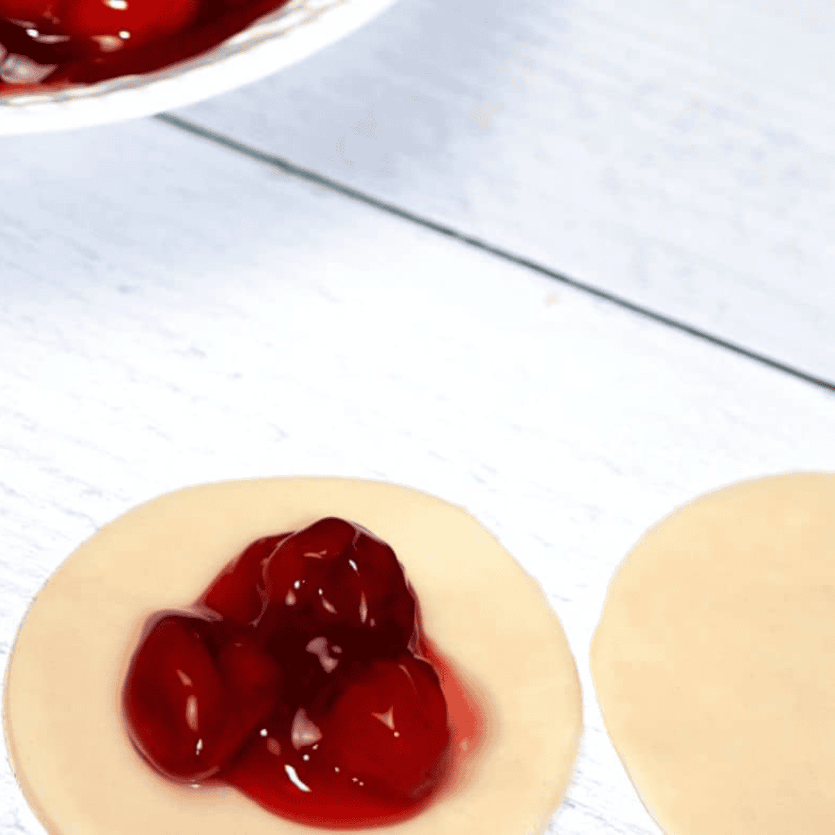 Adding a small amount of cherry filling to the center of a dough circle