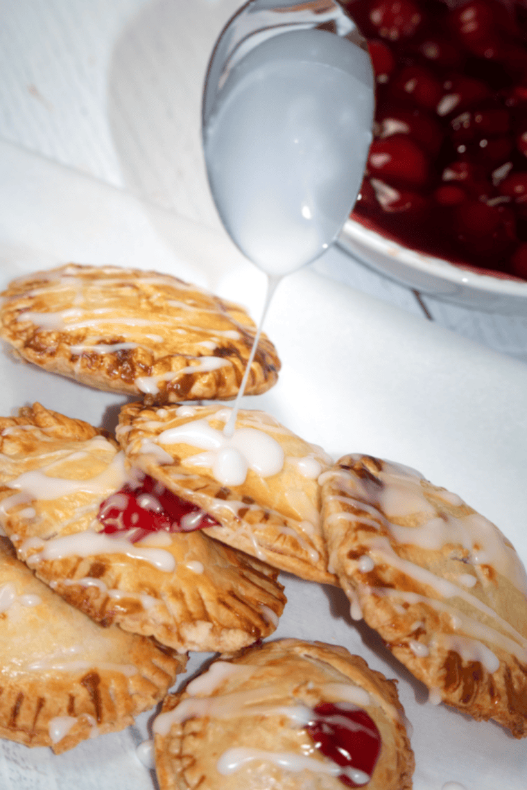Mixing powdered sugar and water to make glaze and drizzling over cooled mini cherry pies