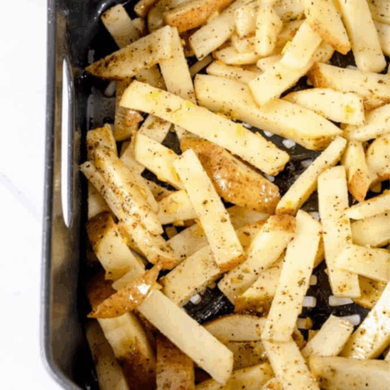 Seasoned fries arranged in a single layer in the air fryer basket before cooking