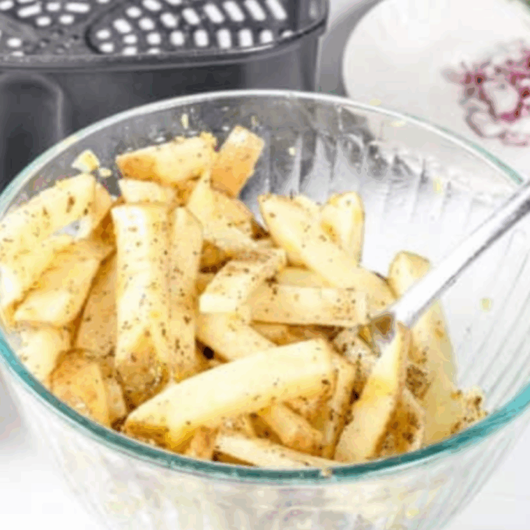 Hand-cut fries tossed with olive oil, lemon zest, and Greek seasoning in a large mixing bowl