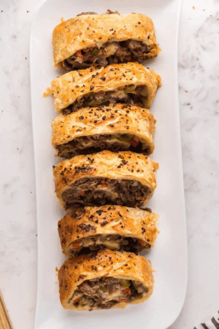 Golden-brown Italian Beef Stromboli sliced open, showing tender beef, sautéed peppers and onions, and melted provolone cheese inside.