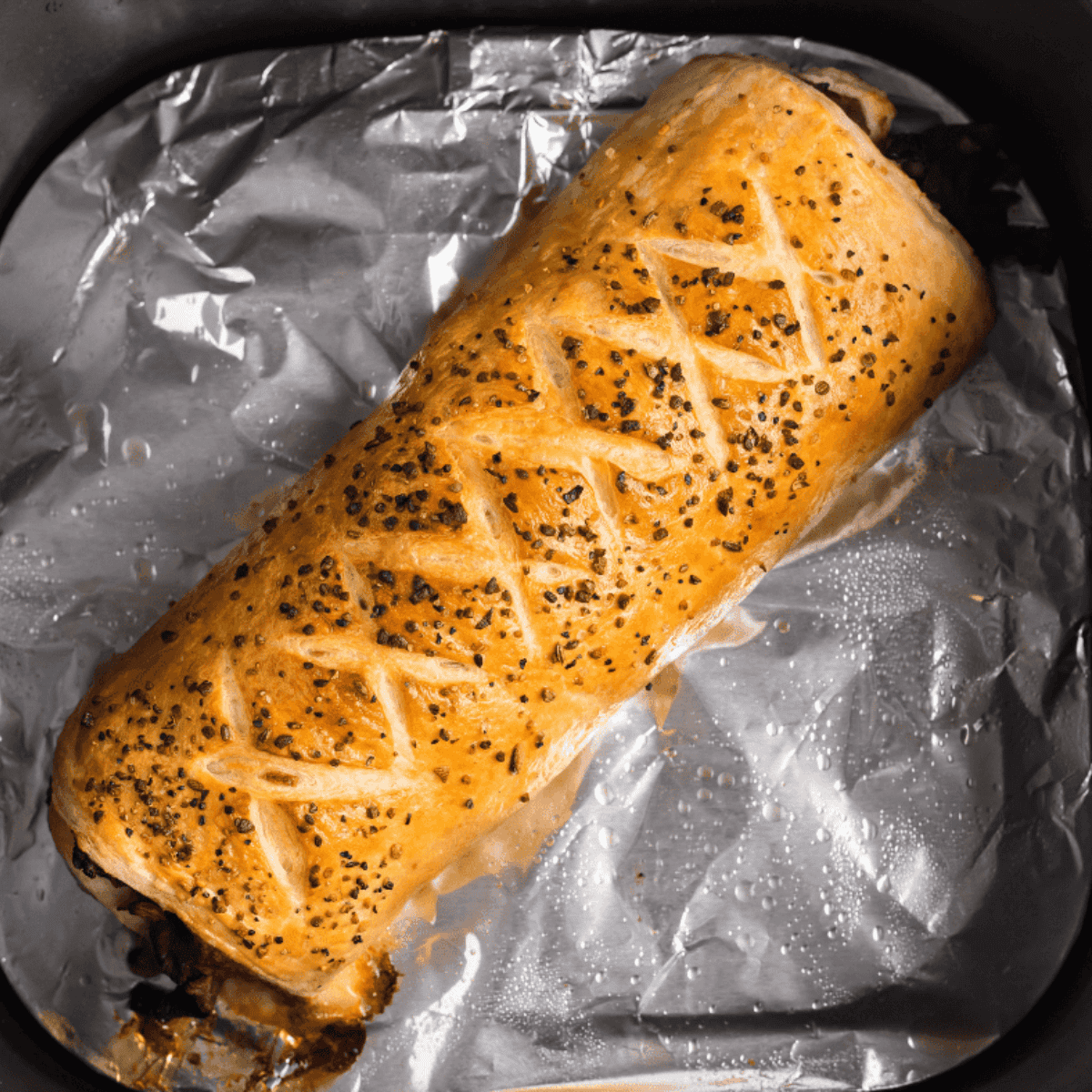 Golden-brown Italian Beef Stromboli sliced open, showing tender beef, sautéed peppers and onions, and melted provolone cheese.