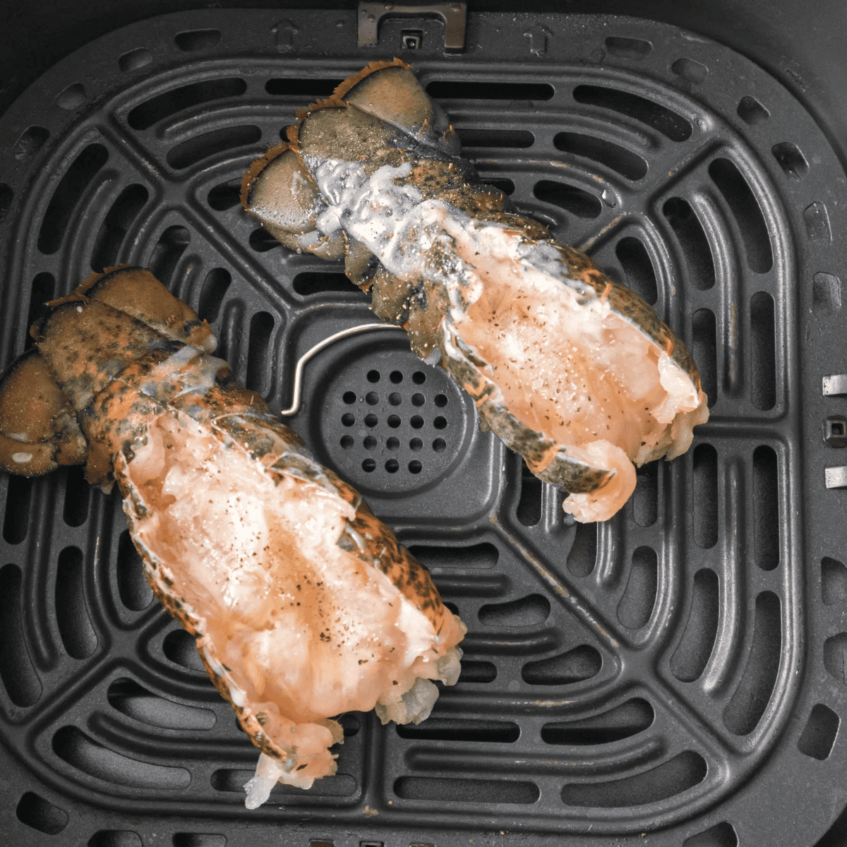Frozen lobster tails in the air fryer basket.