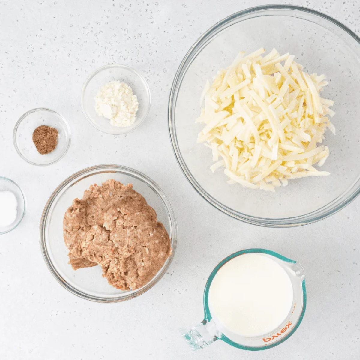 Ingredients for air fryer sausage gravy breakfast skillet: ground breakfast sausage, frozen shredded hash browns, all-purpose flour, milk, salt, and black pepper