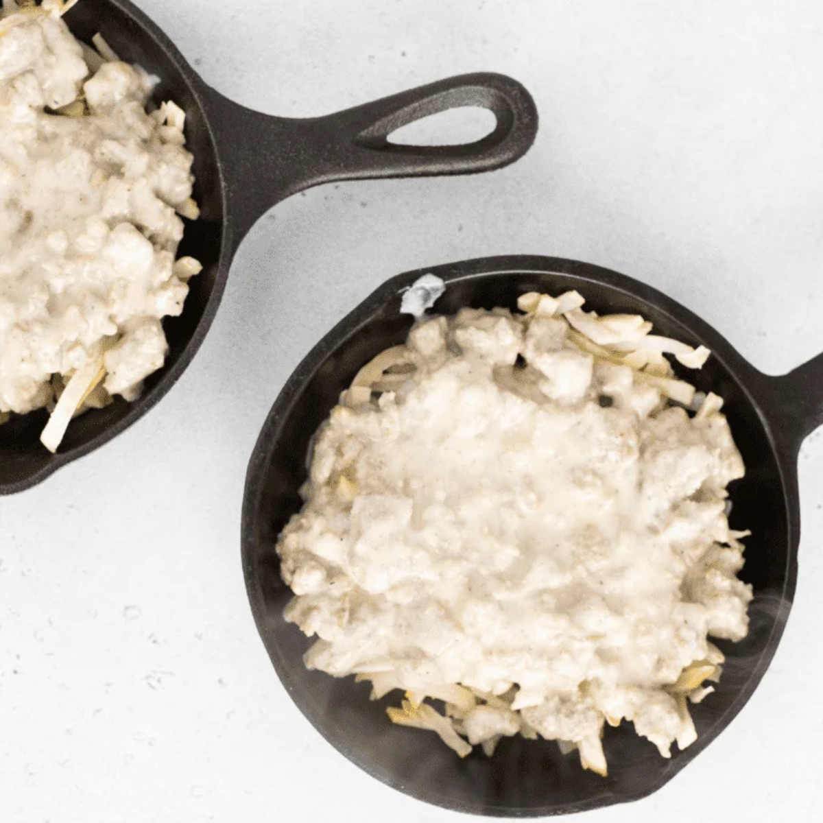 Crispy air-fried hash browns topped with sausage gravy in a baking pan, going into the air fryer