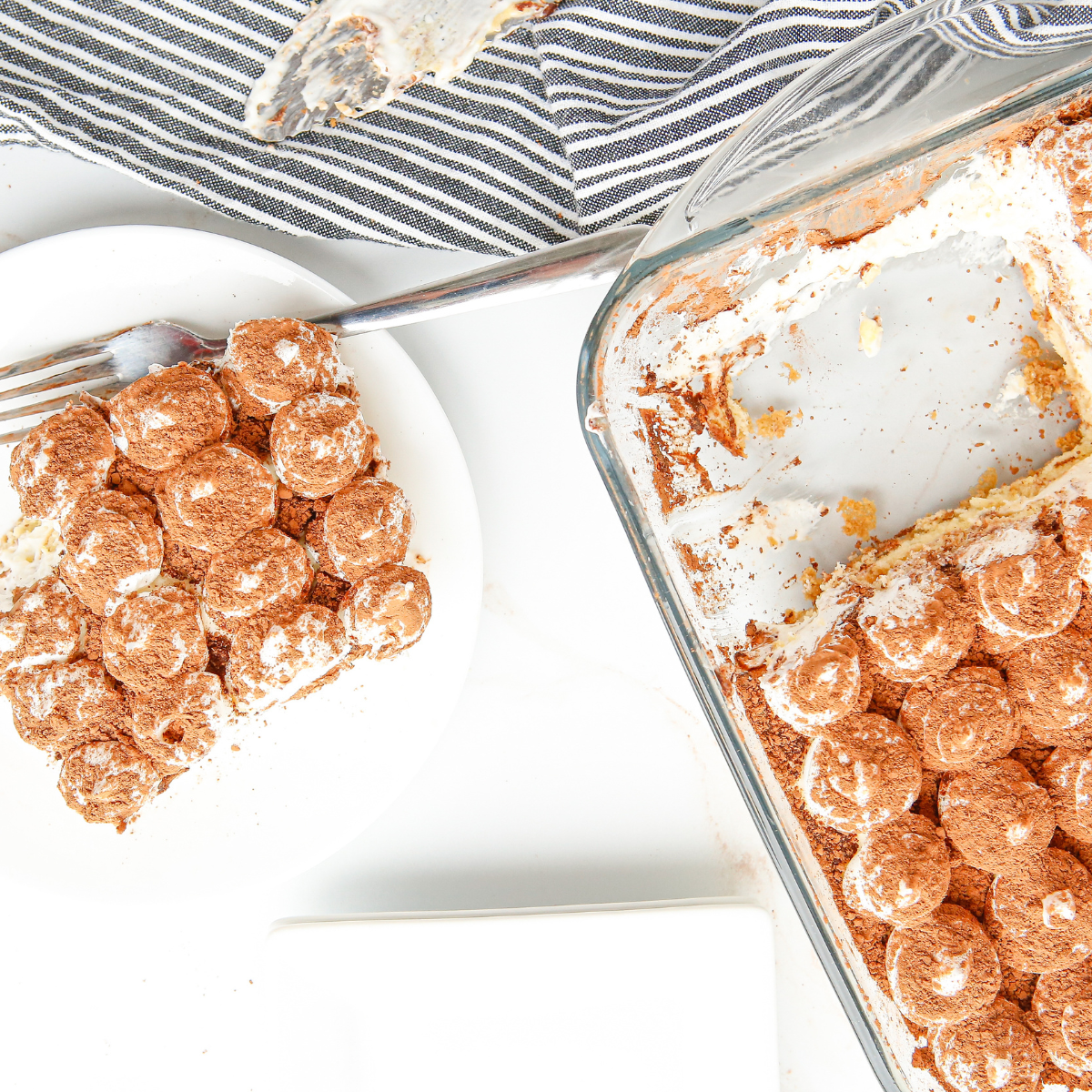 Finished air fryer tiramisu in a square dish dusted with cocoa powder with one slice removed