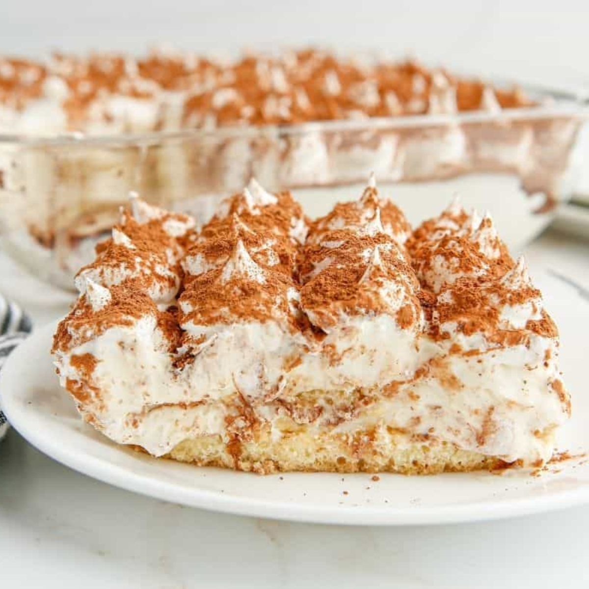 Slice of air fryer tiramisu on a white plate showing layers of espresso-soaked ladyfingers and mascarpone cream dusted with cocoa