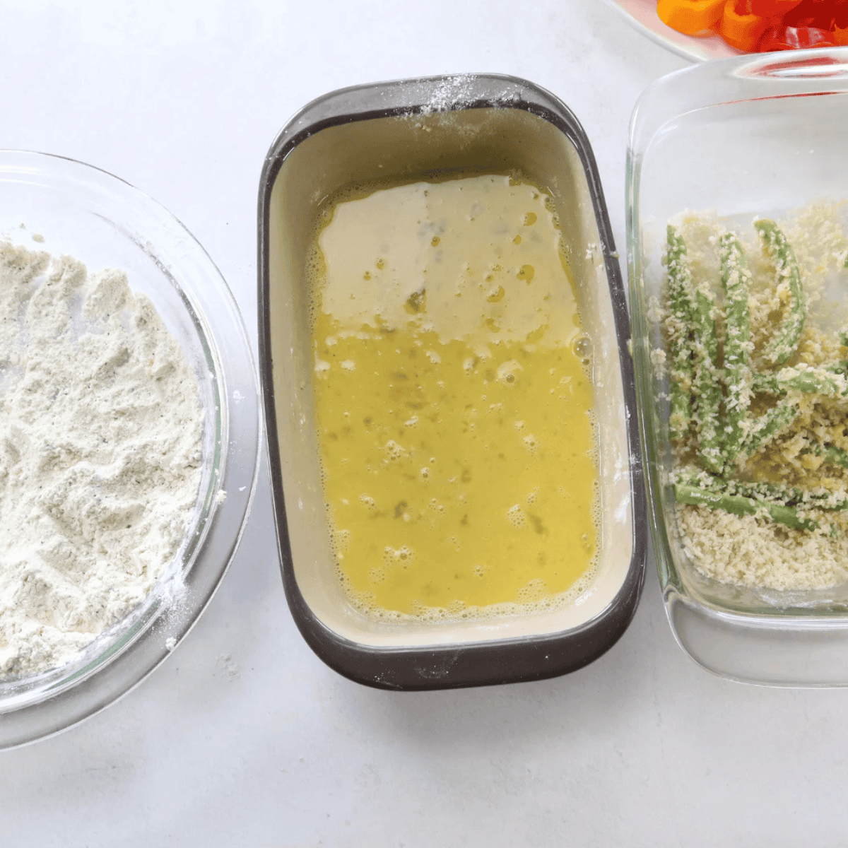 Dipping a zucchini round in tempura batter then pressing it into oiled panko breadcrumbs