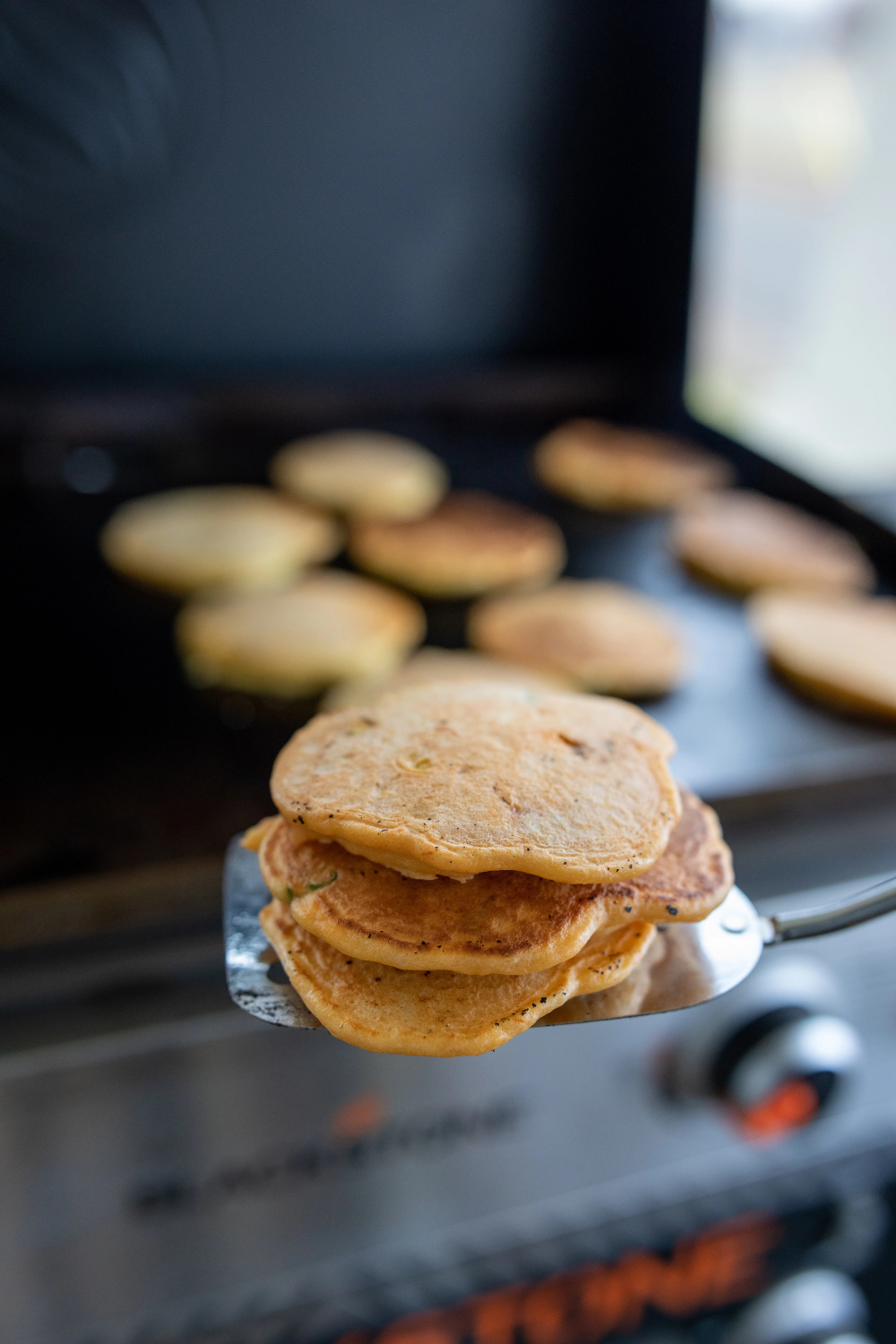 Blackstone griddle corn cakes recipe pin with a stack of golden corn cakes and honey butter