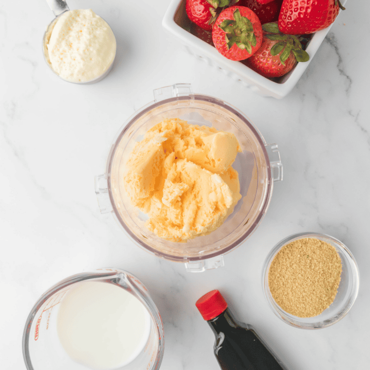 Ingredients for a Ninja Creami strawberry milkshake: vanilla ice cream, milk, and fresh strawberries