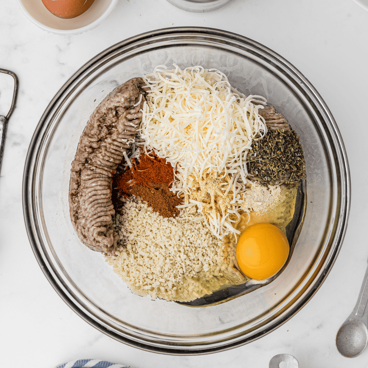 Mixing ground turkey, parmesan, eggs, and herbs in a large bowl
