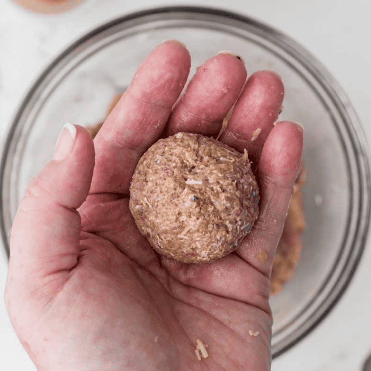 Rolling turkey meatball mixture into balls on a baking sheet