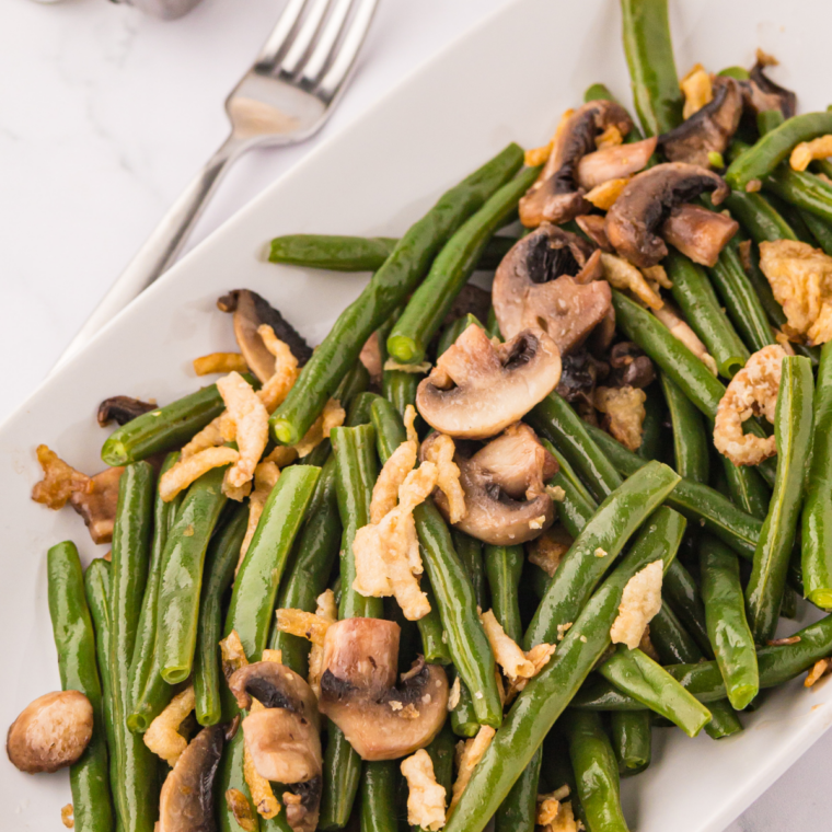 Blackstone green beans sizzling on a flat top griddle with garlic and seasoning