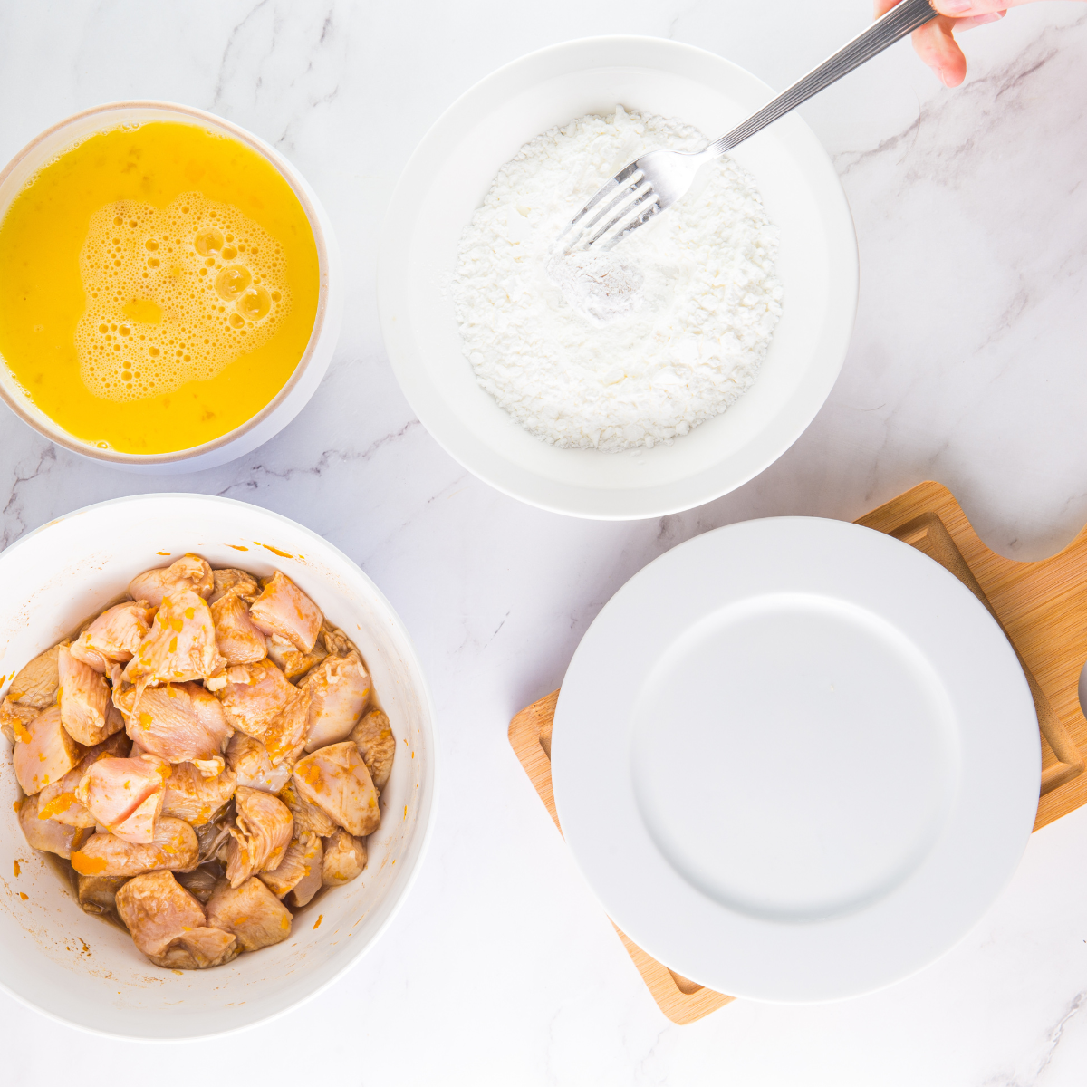 Coating chicken pieces by dipping in eggs and flour-cornstarch mixture