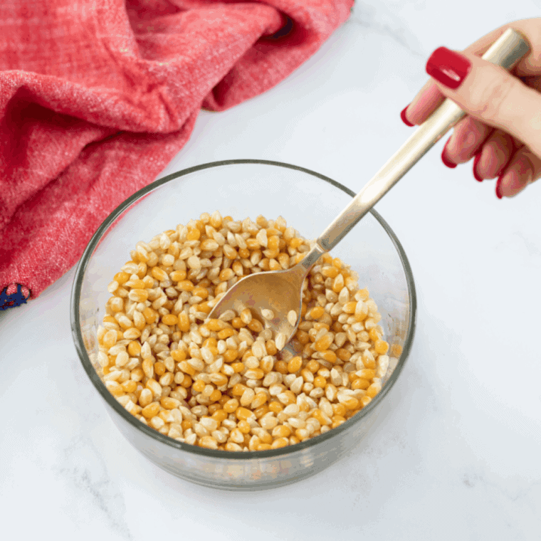 Popcorn kernels tossed with oil in a small mixing bowl before popping