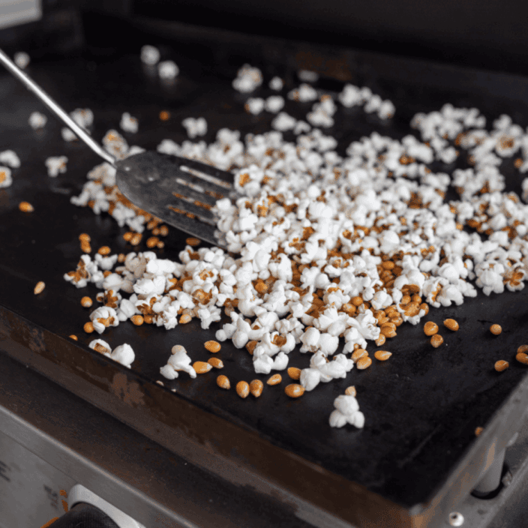 Oiled popcorn kernels spread in a single layer on a hot Blackstone griddle