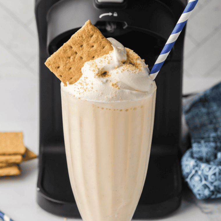 Vanilla milkshake poured into a chilled glass and topped with whipped cream and a cherry