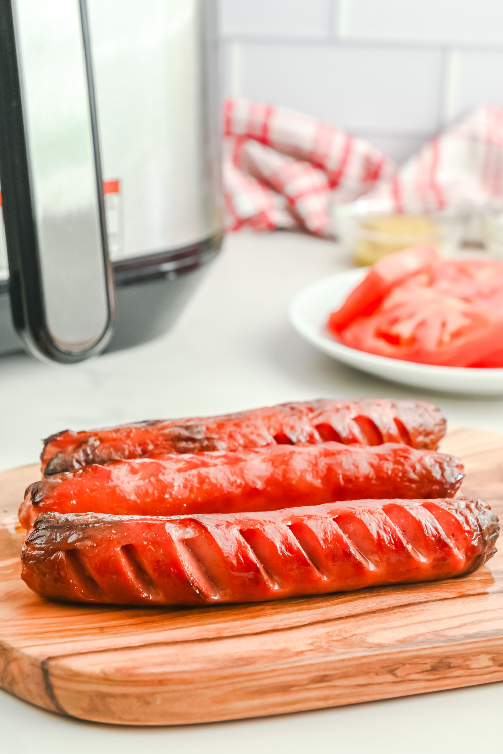 Hot dogs reheating in an air fryer basket with slightly crisped edges and evenly warmed centers.