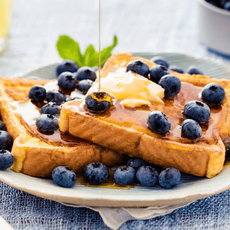 Air fryer eggless French toast slices, golden brown and crispy, served on a plate with syrup and fresh fruit