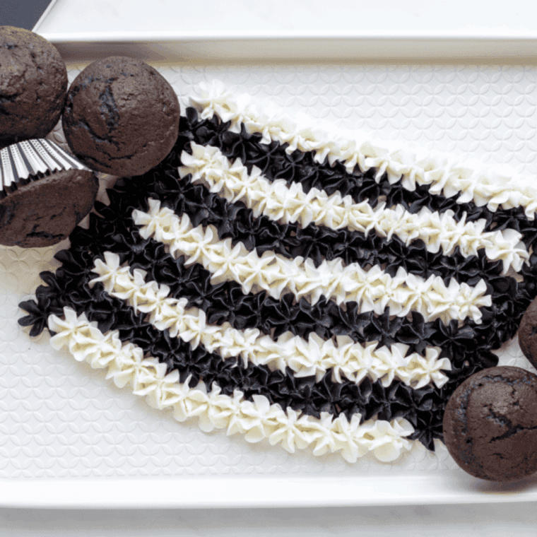 Placing brownie bites and chocolate cupcakes onto the dessert board, positioned closely but not touching the frosting.