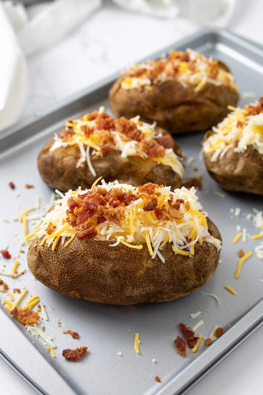 Cooked baked potatoes sliced open, topped with butter and sour cream.