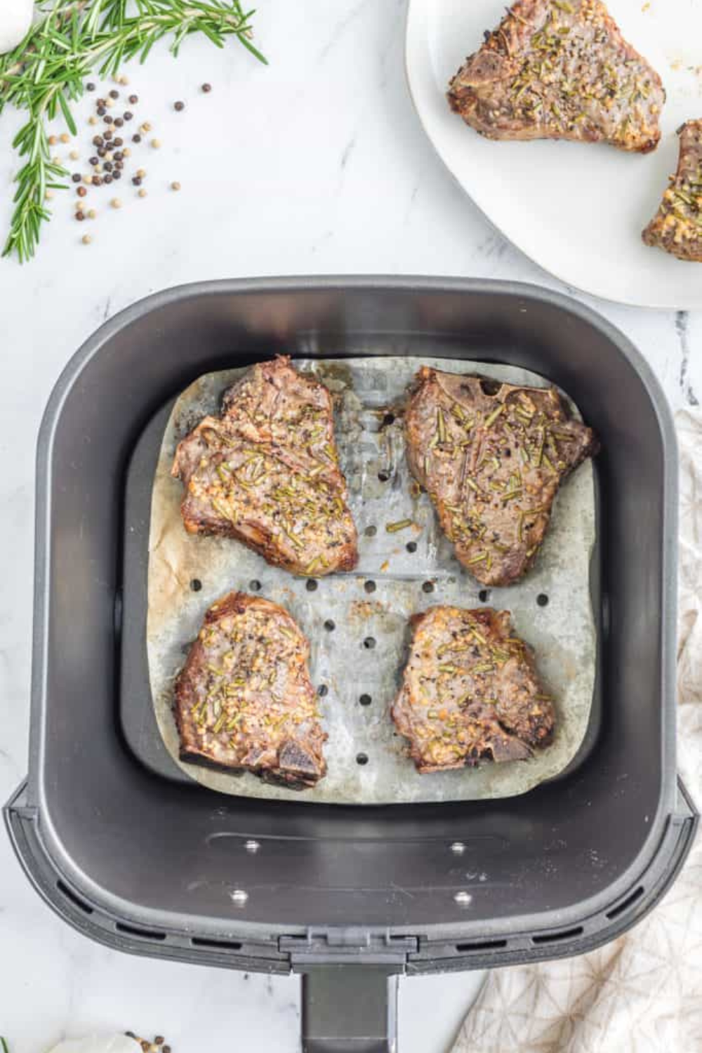 Cooked lamb chops in an air fryer basket being reheated