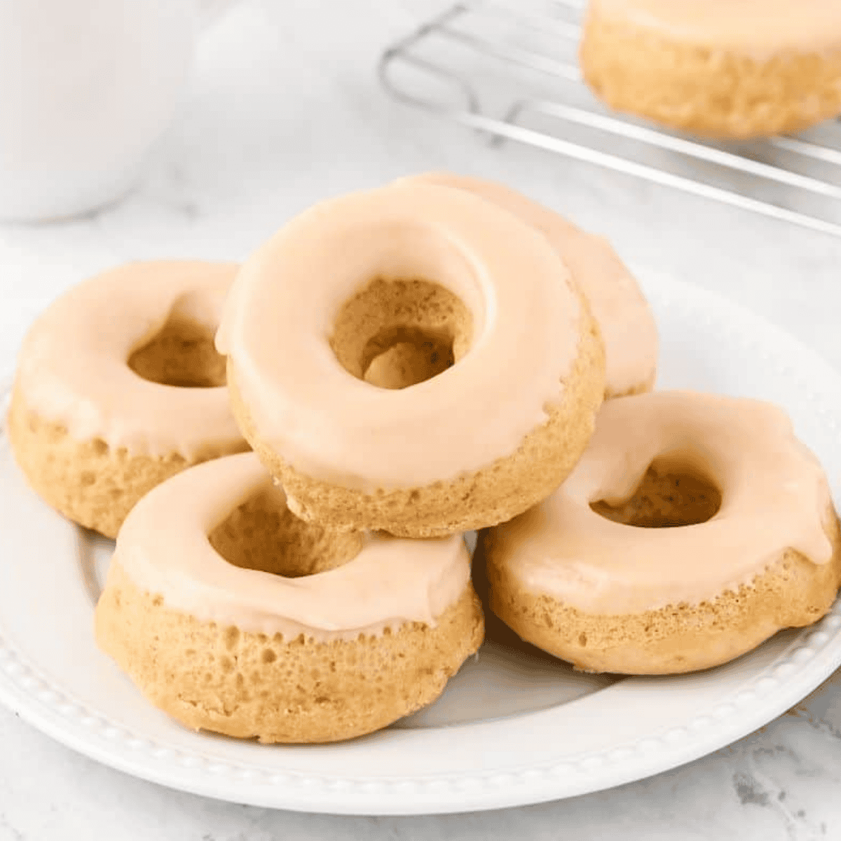 Dipping a cooled air fryer protein donut into Greek yogurt glaze