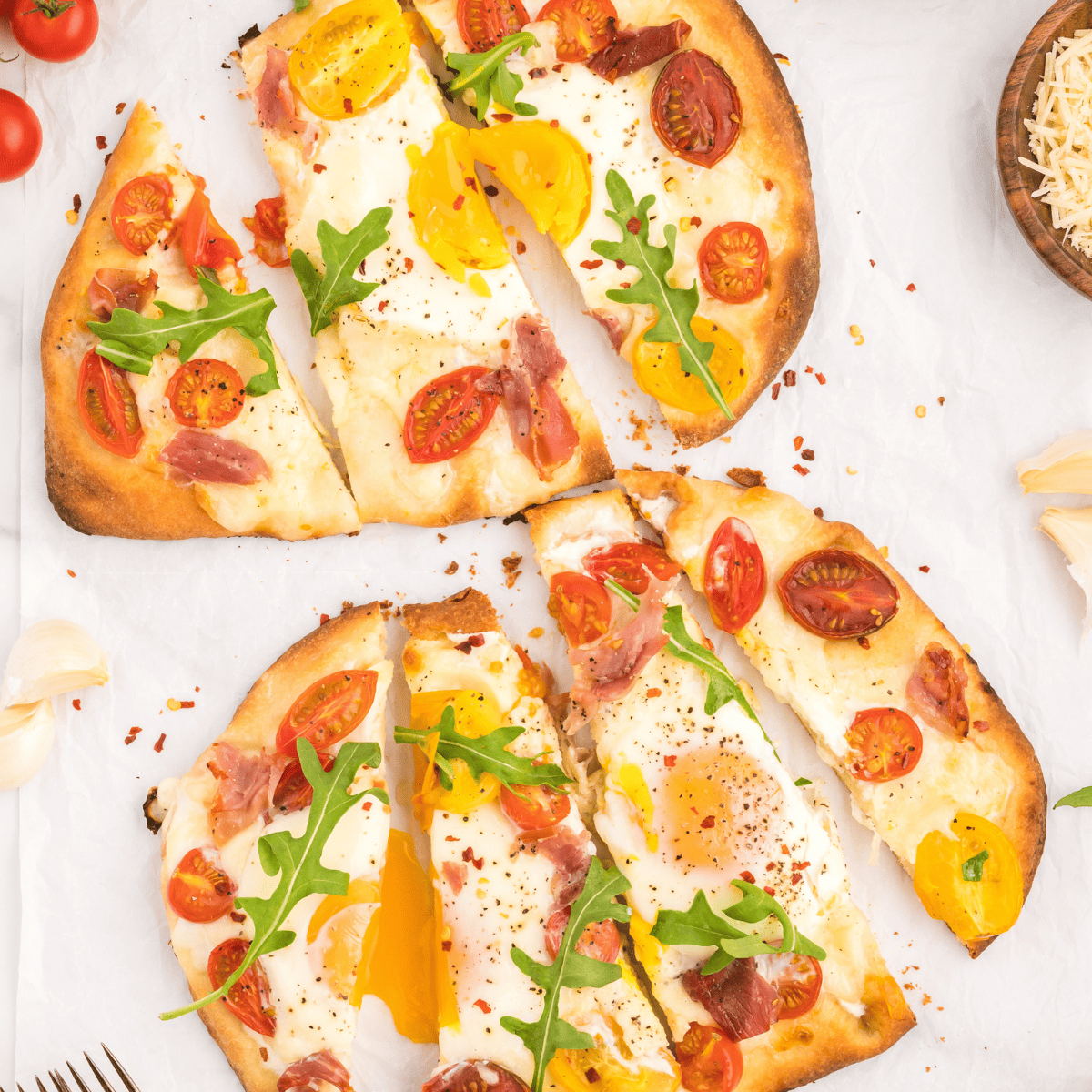 Air Fryer Breakfast Flatbread Pizza topped with eggs, prosciutto, and cherry tomatoes.