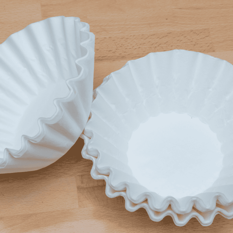Pile of white paper coffee filters stacked on a wooden table