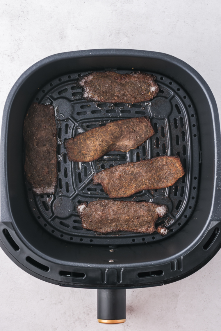 Finished air fryer Trader Joe's gyro slices with darkened, curled edges in the basket