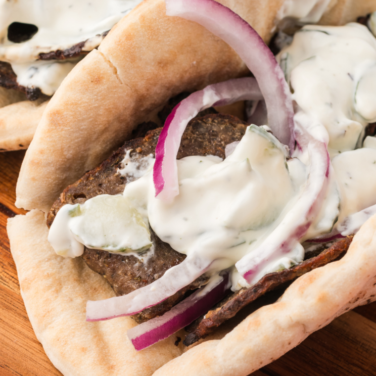Two Trader Joe's gyro sandwiches wrapped in parchment on a wooden board